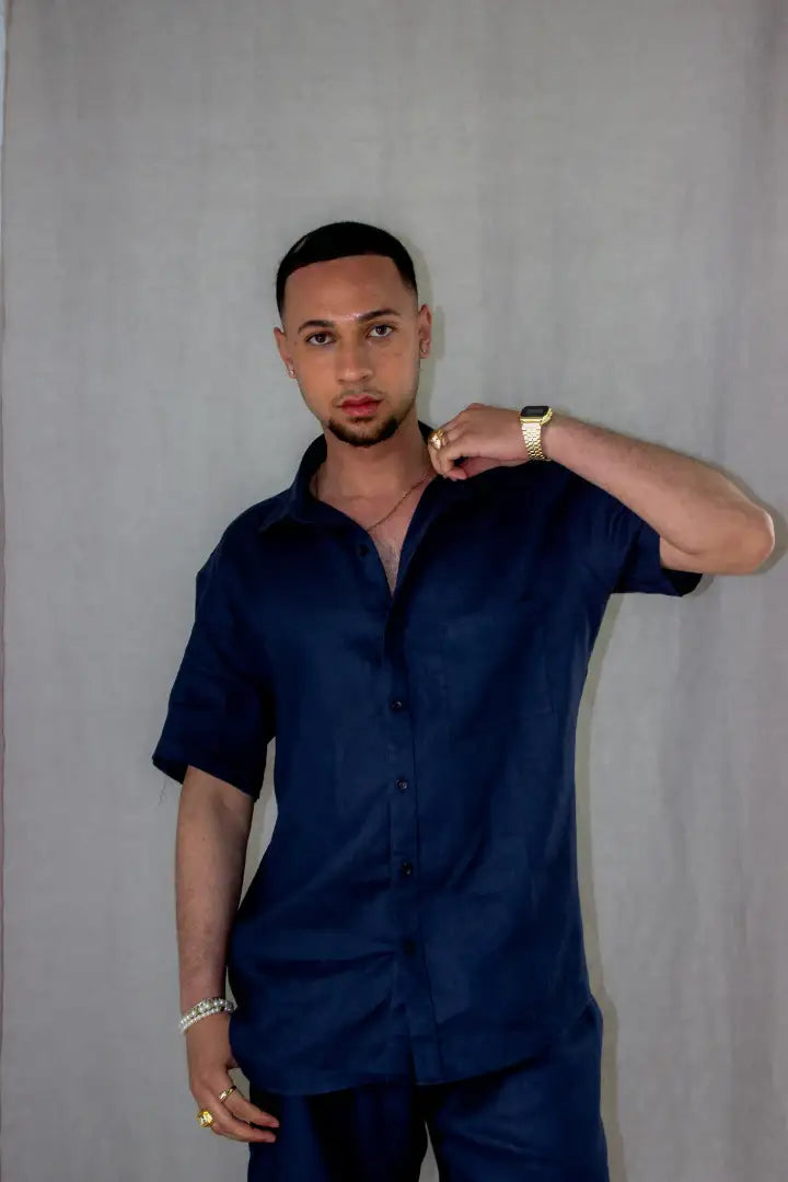 Man wearing a navy blue linen shirt and pants against a gray background