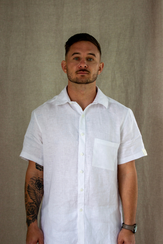 Man wearing a white linen short-sleeve shirt against a beige background