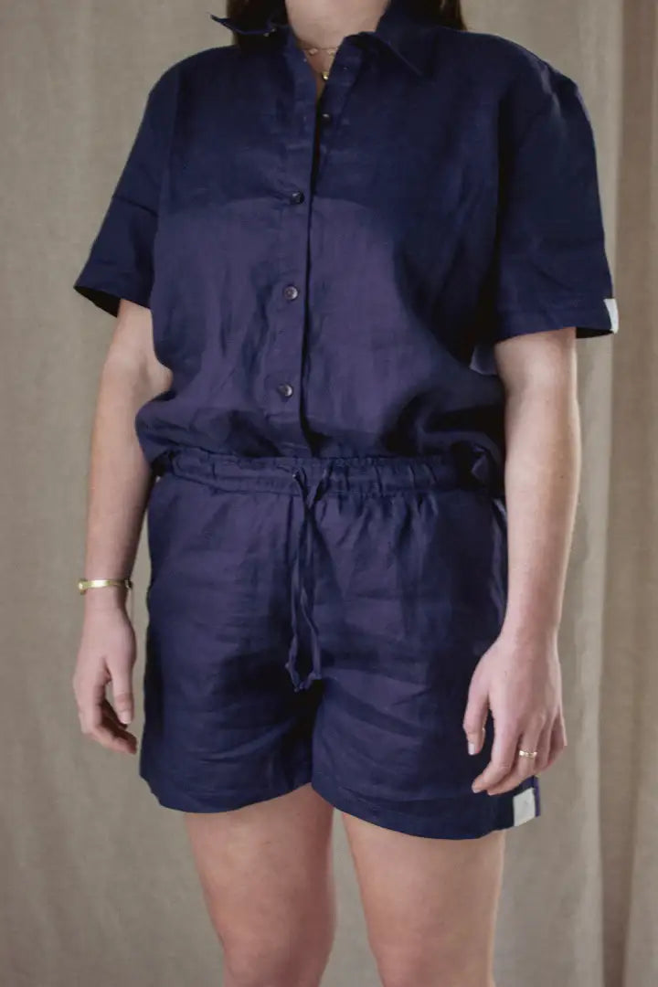 Person wearing a navy blue romper against a plain background