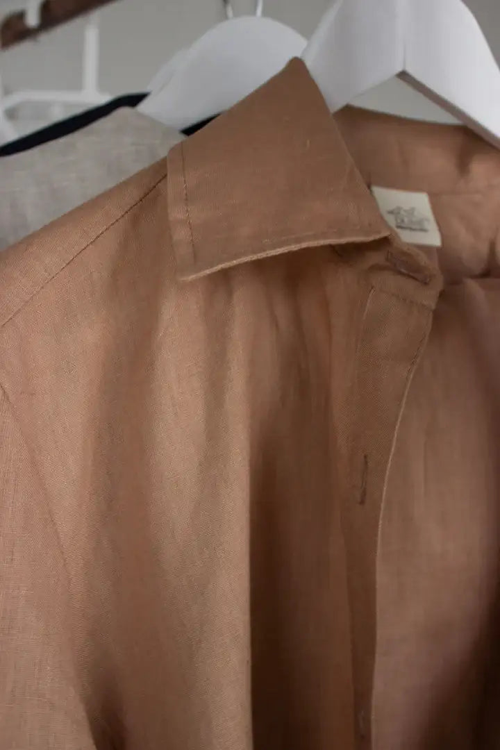 Brown linen shirt on a hanger with a visible brand label.
