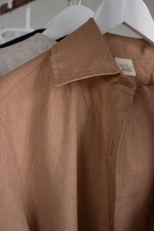 Brown linen shirt on a hanger with a visible brand label.